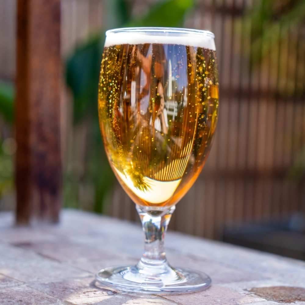 The Polycarbonate Goblet Glass 380ml  is full of beer poured from a booze tower beer tower. its sitting on a table outside