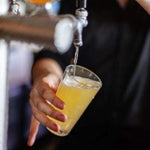 A bartender is pouring a beer into a Polycarbonate 570ml Highball Beer Glasses Nucleated and Certified. These glasses pair perfectly with a booze towers beer tower