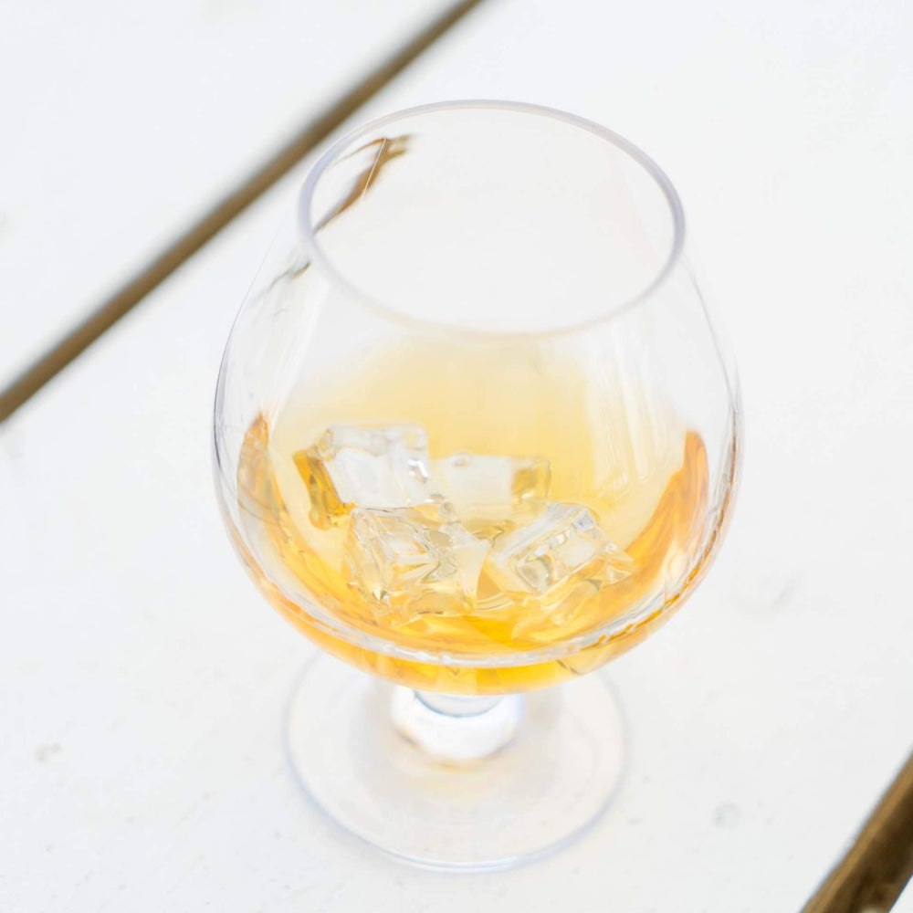 
                  
                     The Polycarbonate Cocktail Goblet 350ml has whiskey on the rocks in it and is sitting on a white slatted table. This glass is perfect for cocktails from the booze towers cocktail tower
                  
                